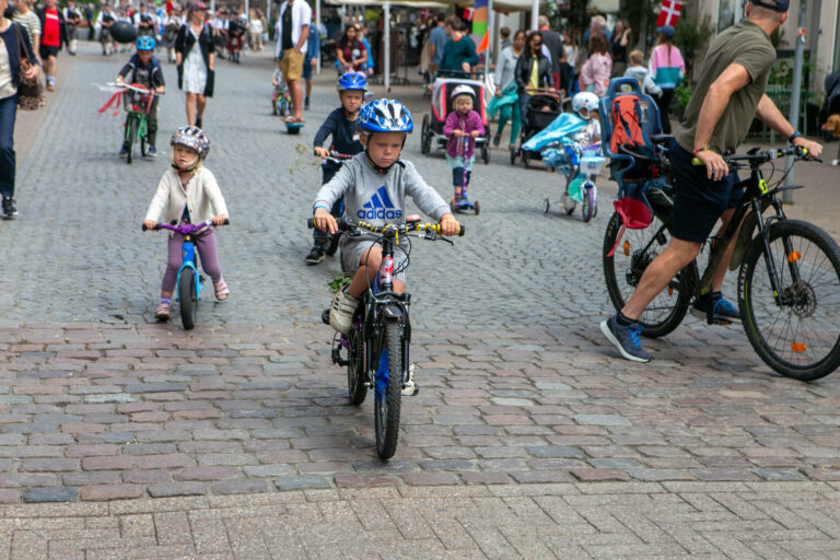 Glade børn på cykel gennem gågaden