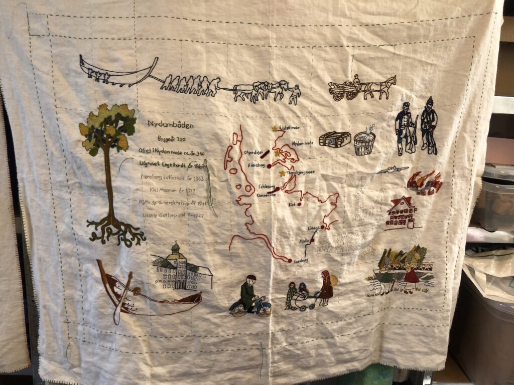 Broderede tæpper illustrerer fortællingen om Nydam Mose